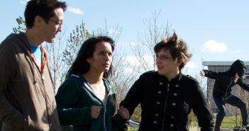Three young people walk outside while talking.